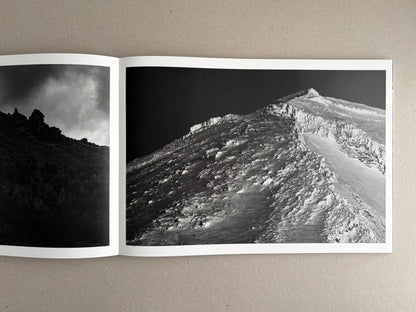 Open photobook spread from New Land: Pre-Hokkaido Landscapes by Toshiki Nakanishi, showing two black-and-white landscape photographs.