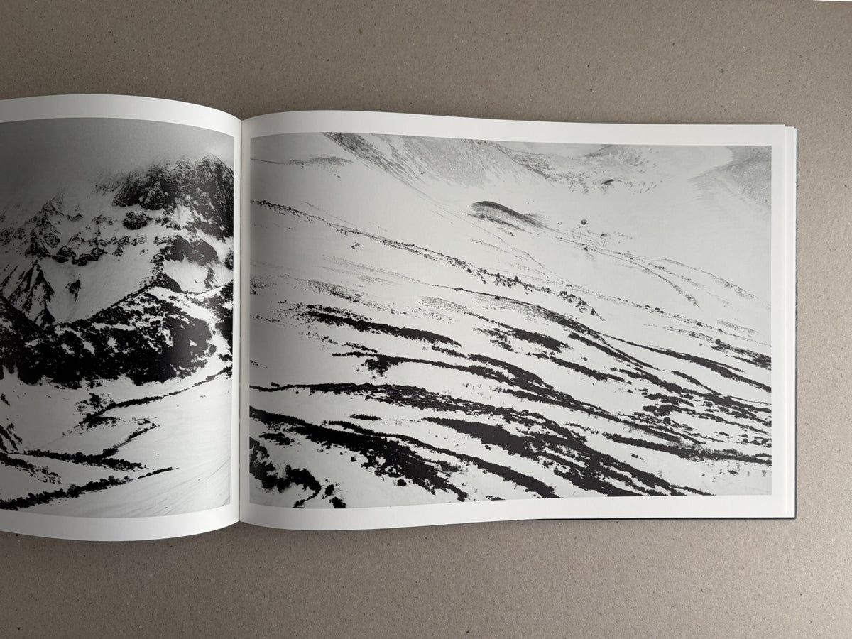 Open photobook spread from New Land: Pre-Hokkaido Landscapes by Toshiki Nakanishi, showing black-and-white mountain landscapes across two pages.