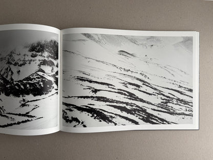 Open photobook spread from New Land: Pre-Hokkaido Landscapes by Toshiki Nakanishi, showing black-and-white mountain landscapes across two pages.