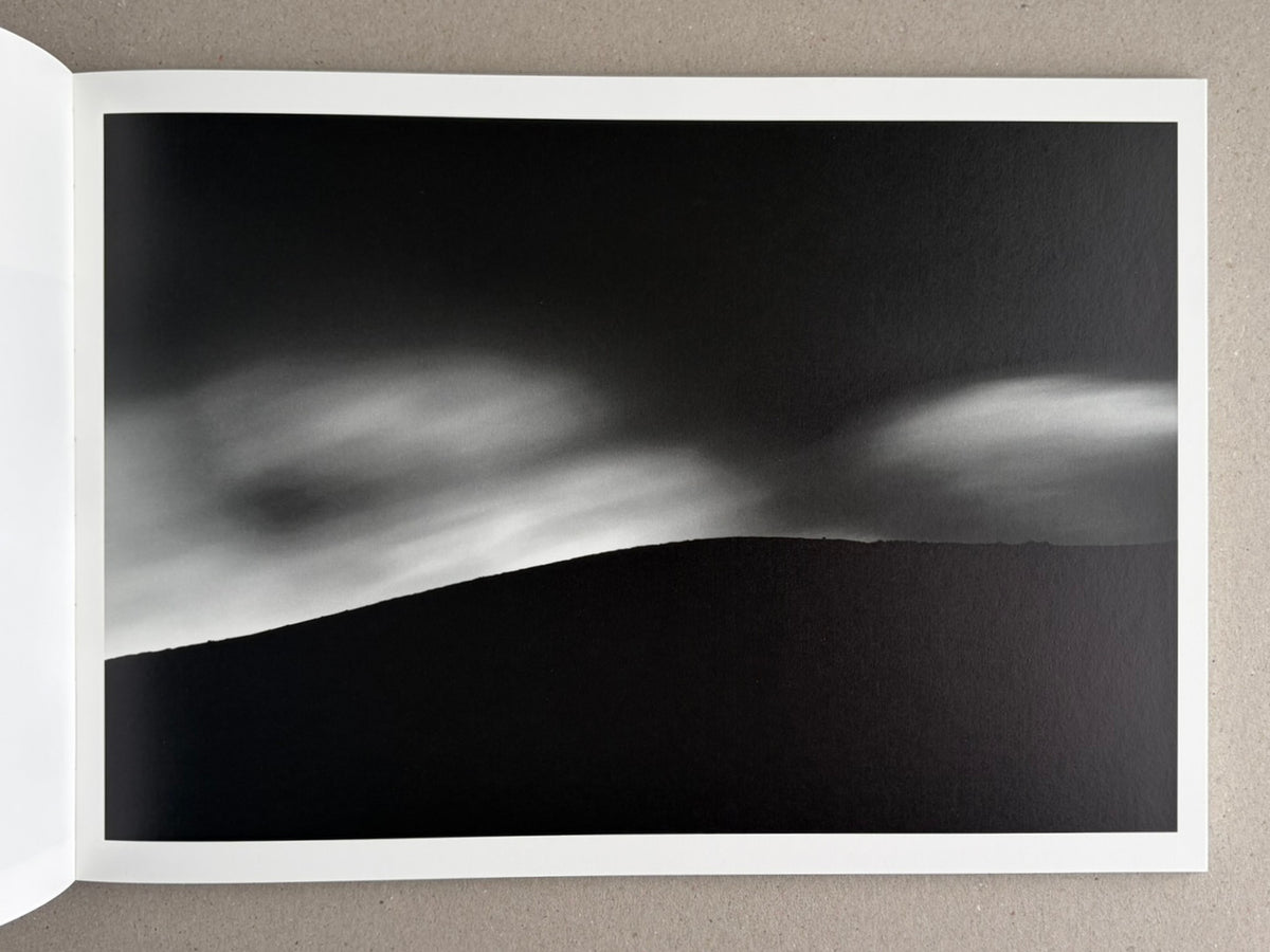 Open photobook spread from New Land: Pre-Hokkaido Landscapes by Toshiki Nakanishi, showing a black-and-white landscape image.