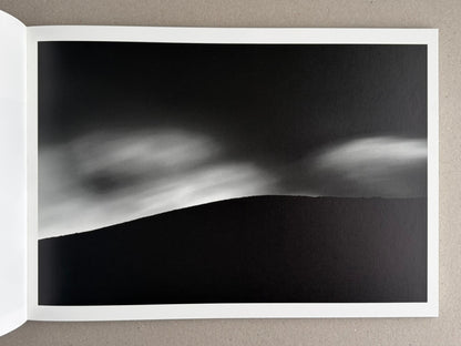 Open photobook spread from New Land: Pre-Hokkaido Landscapes by Toshiki Nakanishi, showing a black-and-white landscape image.