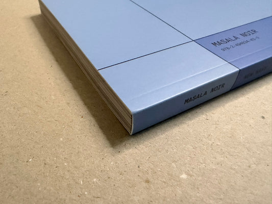 Close-up of the book’s spine and page edges, showing the pale blue cover and Masala Noir imprint.