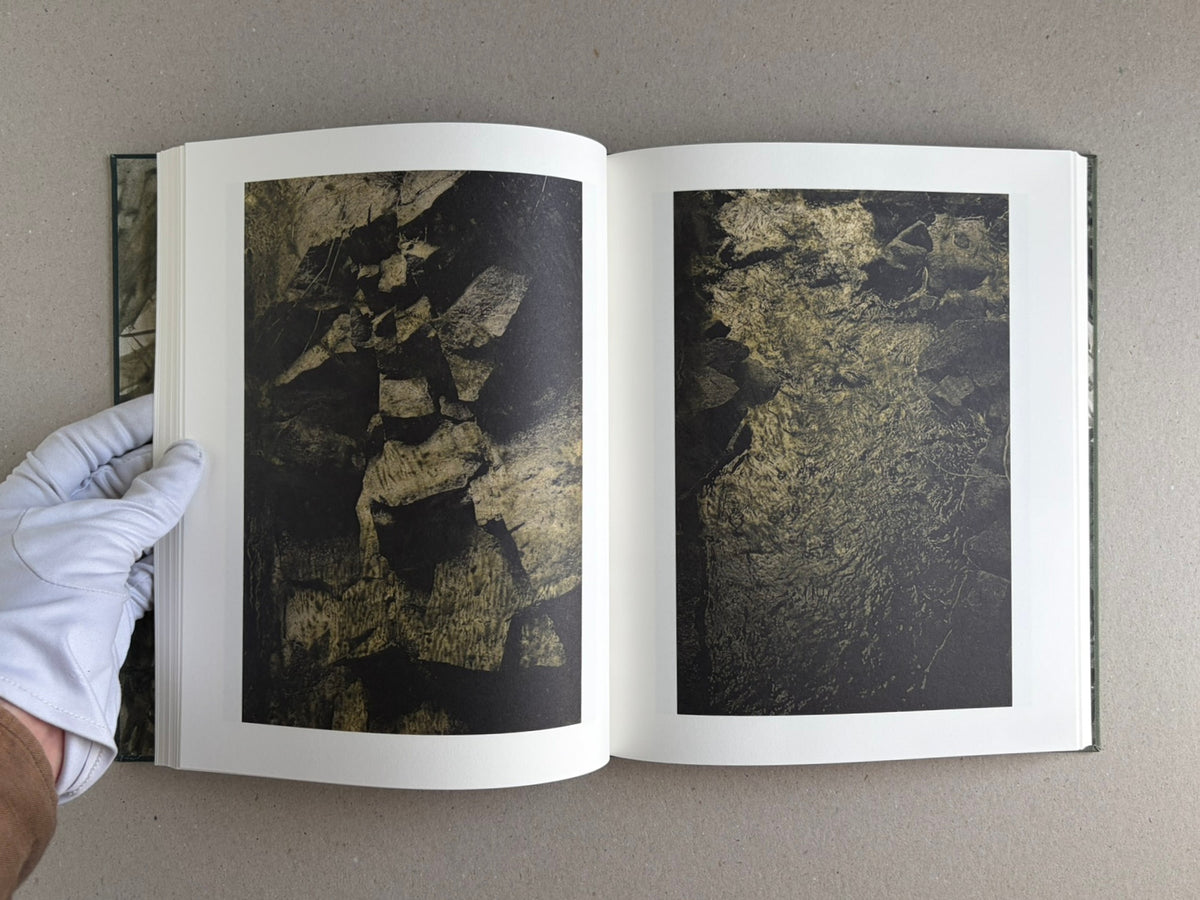Open Night Procession by Stephen Gill, showing a two-page spread of dark photographic images on white pages, with a gloved hand holding the book open.