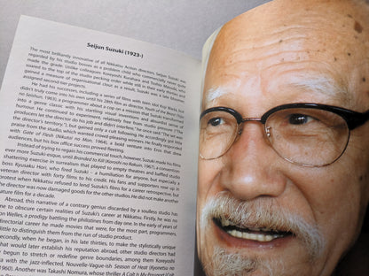 Close-up color photo of director Seijun Suzuki with biographical text on his Nikkatsu Action films.