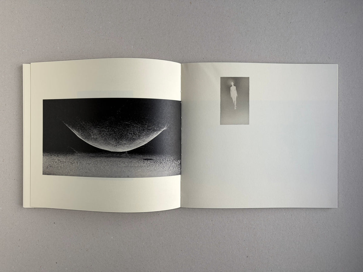 Nusa by Masao Yamamoto, open spread with a dark abstract image and a small figure