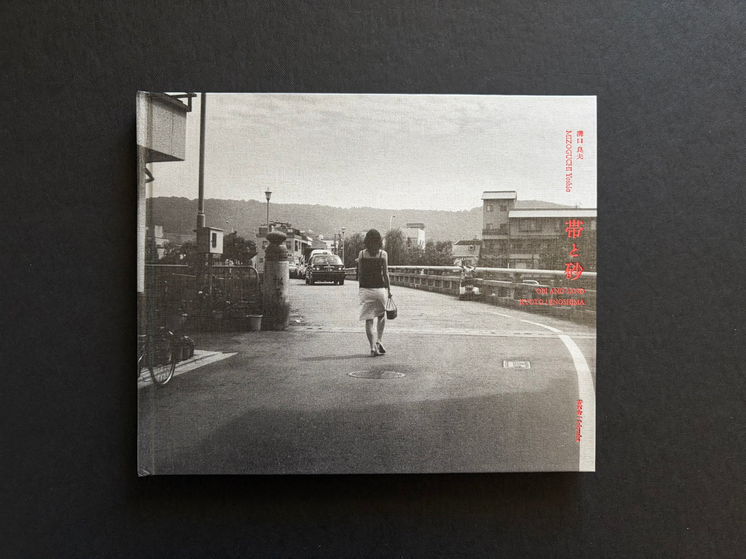 Front cover of *Obi and Sand: Kyoto/Enoshima* by Yoshio Mizoguchi, with a black-and-white street scene and red title text.
