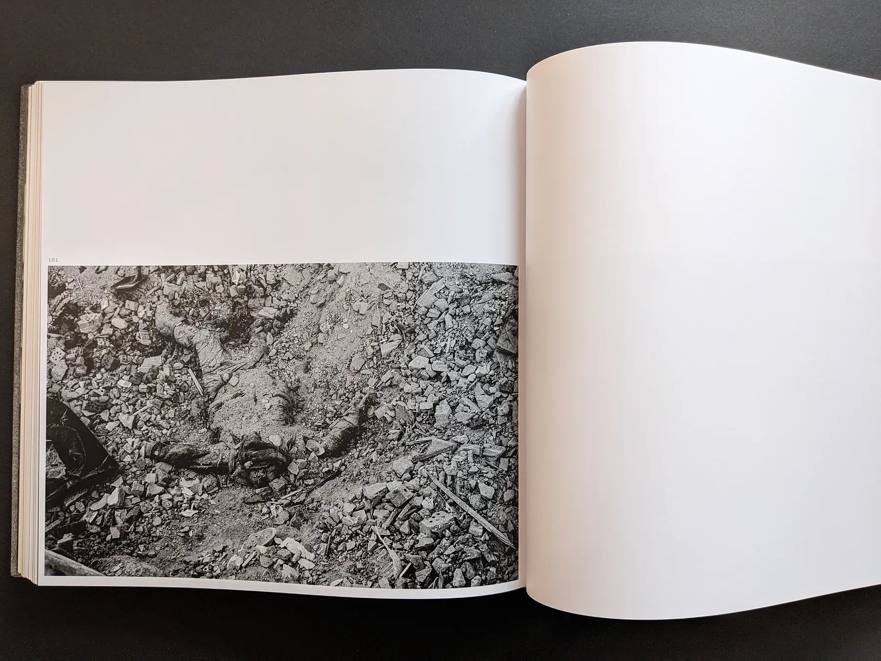 Graphic war image by Oleksandr Glyadyelov showing the body of a victim lying face up amid rubble and broken bricks.