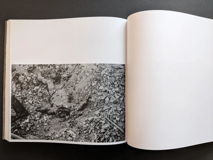 Graphic war image by Oleksandr Glyadyelov showing the body of a victim lying face up amid rubble and broken bricks.