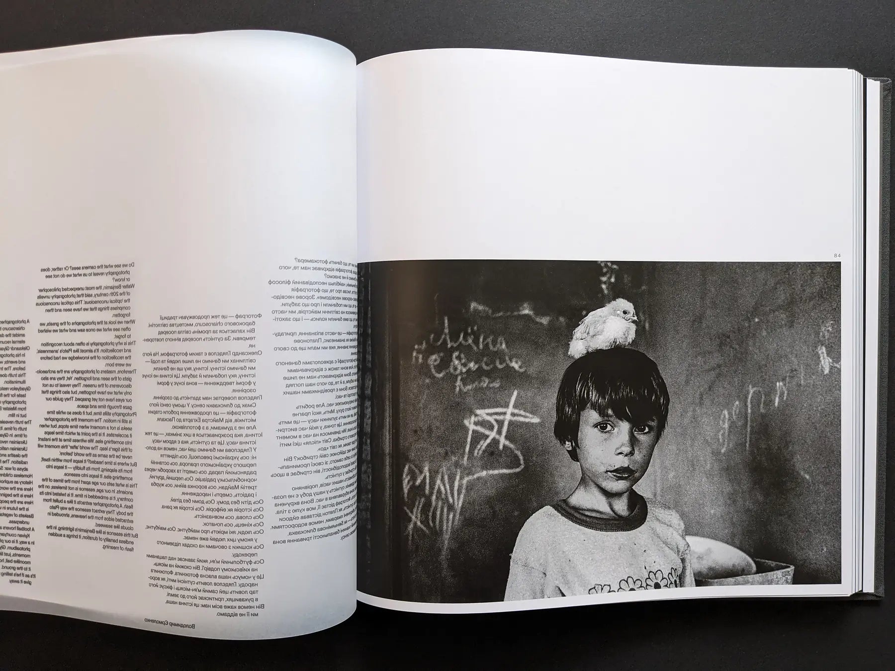 Oleksandr Glyadyelov photograph of a Ukrainian boy indoors with a small white chick sitting on his head, printed next to essay text.