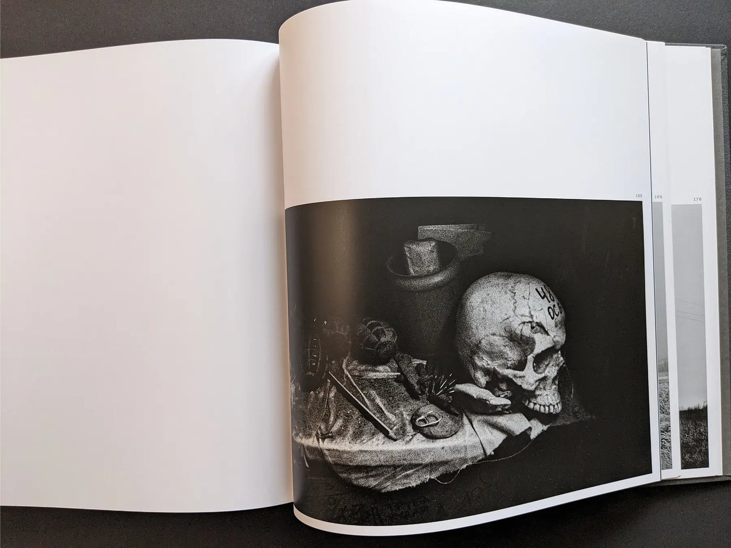 Still life photograph by Oleksandr Glyadyelov depicting a human skull, grenade and small objects arranged on a cloth in stark lighting.