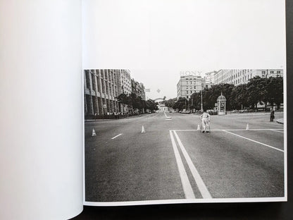 Inside spread from Oleksandr Glyadyelov showing a lone person with crutches crossing a wide, almost empty city avenue.