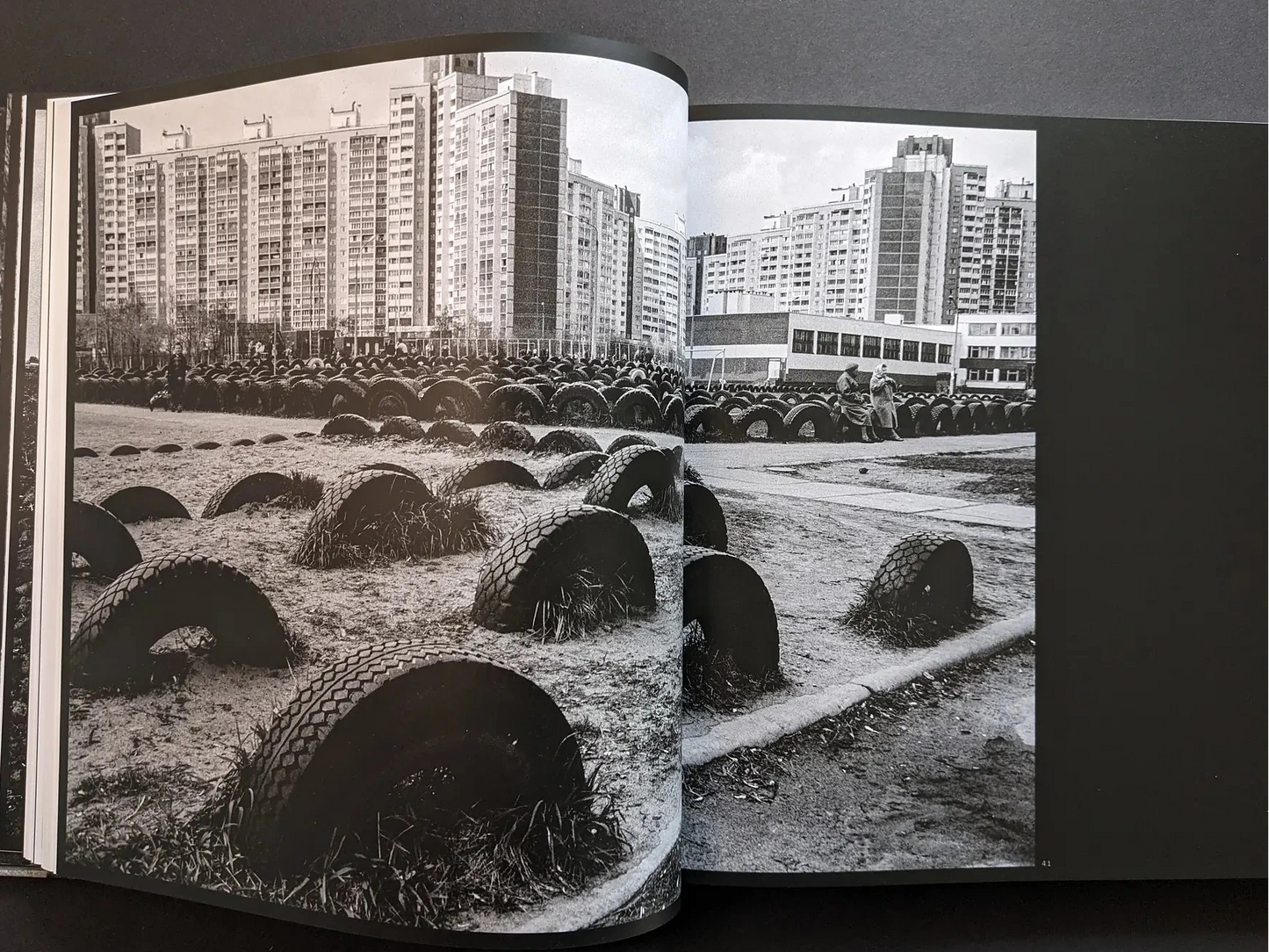 Inside spread from Oleksandr Glyadyelov with rows of half-buried tyres in a playground in front of large apartment blocks.