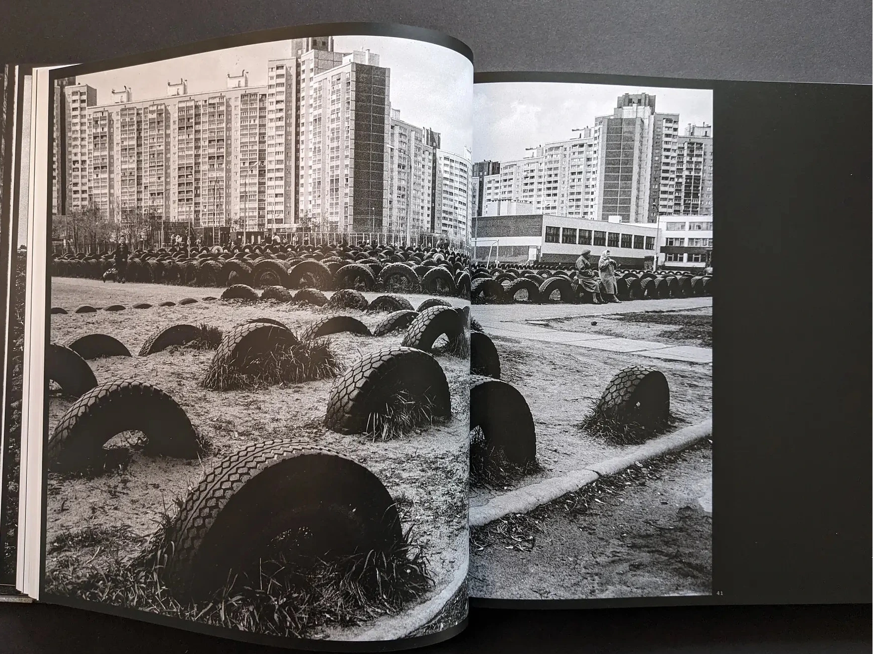 Inside spread from Oleksandr Glyadyelov with rows of half-buried tyres in a playground in front of large apartment blocks.