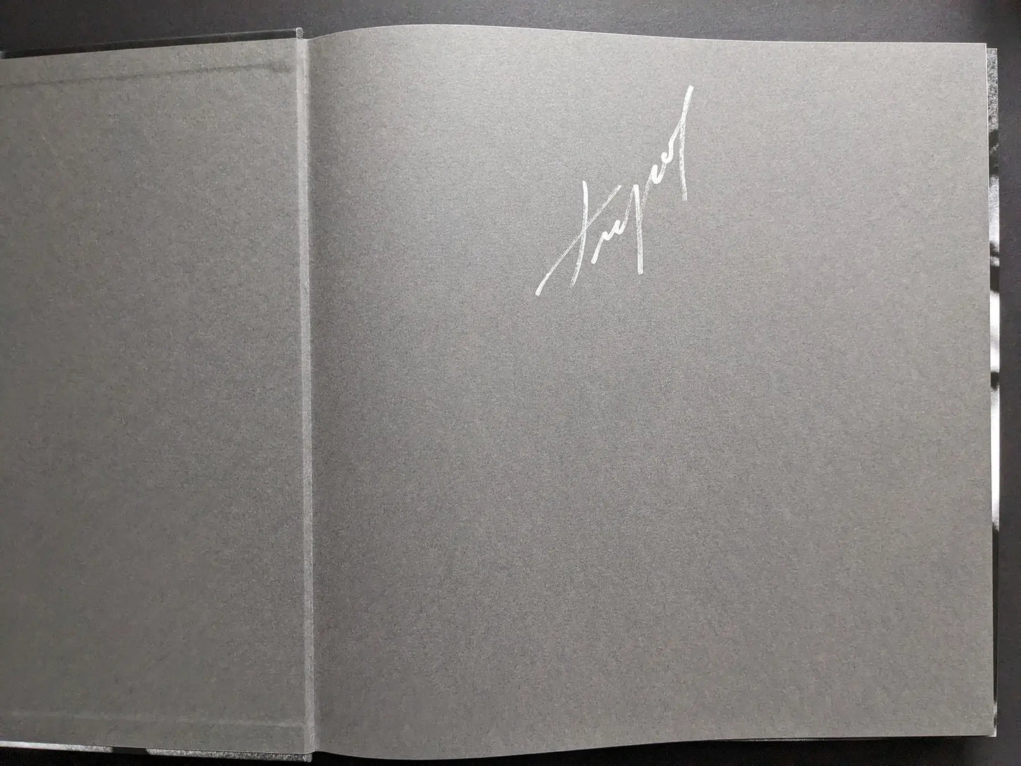 Signed gray endpaper of the “Oleksandr Glyadyelov” photobook with the photographer’s signature in white ink.