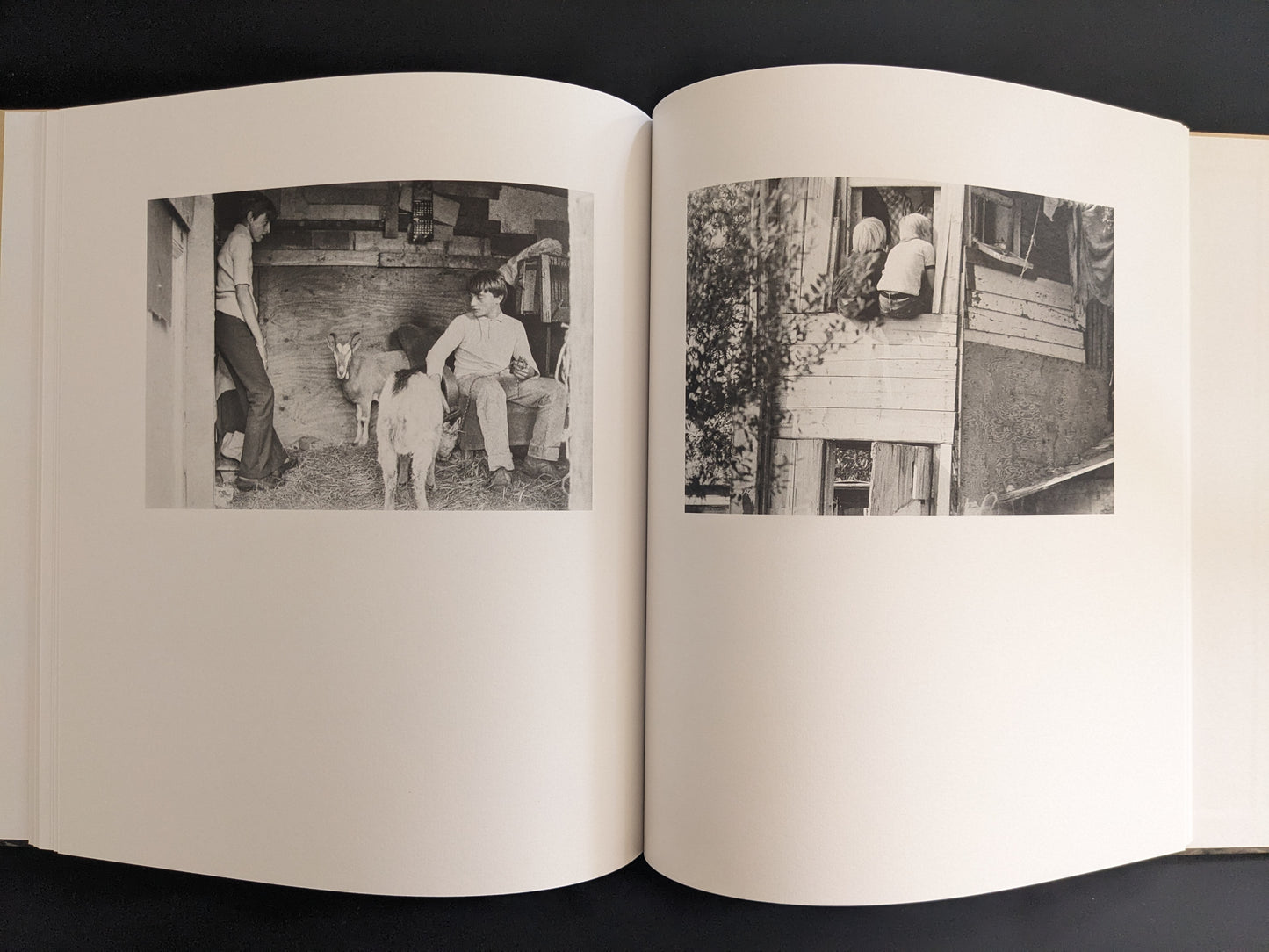 Open spread with black-and-white photographs of children and goats inside improvised huts.