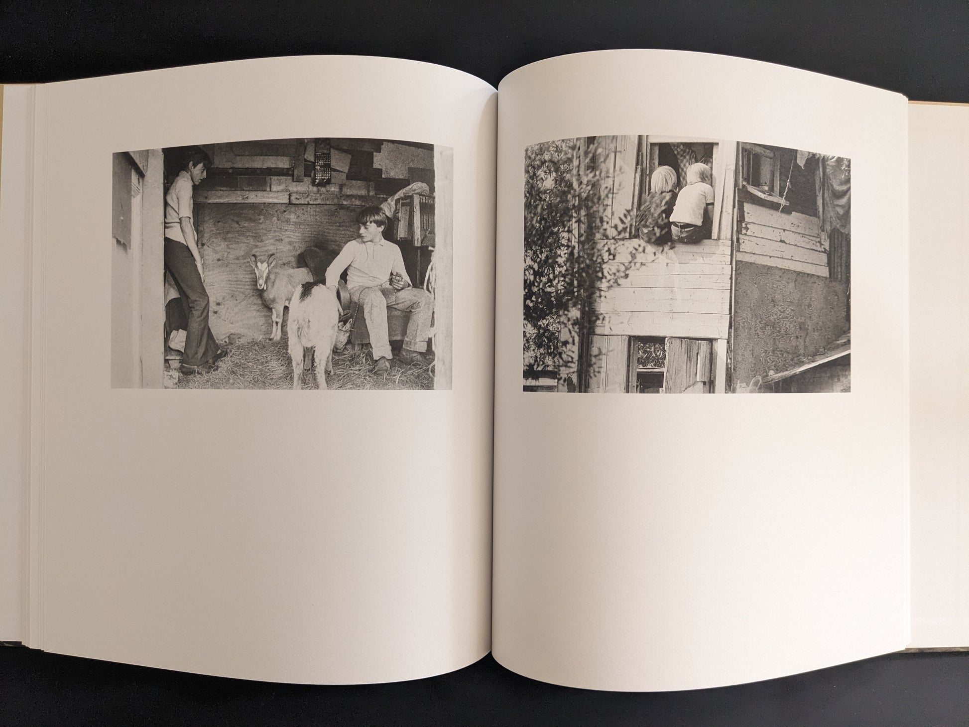 Open spread with black-and-white photographs of children and goats inside improvised huts.
