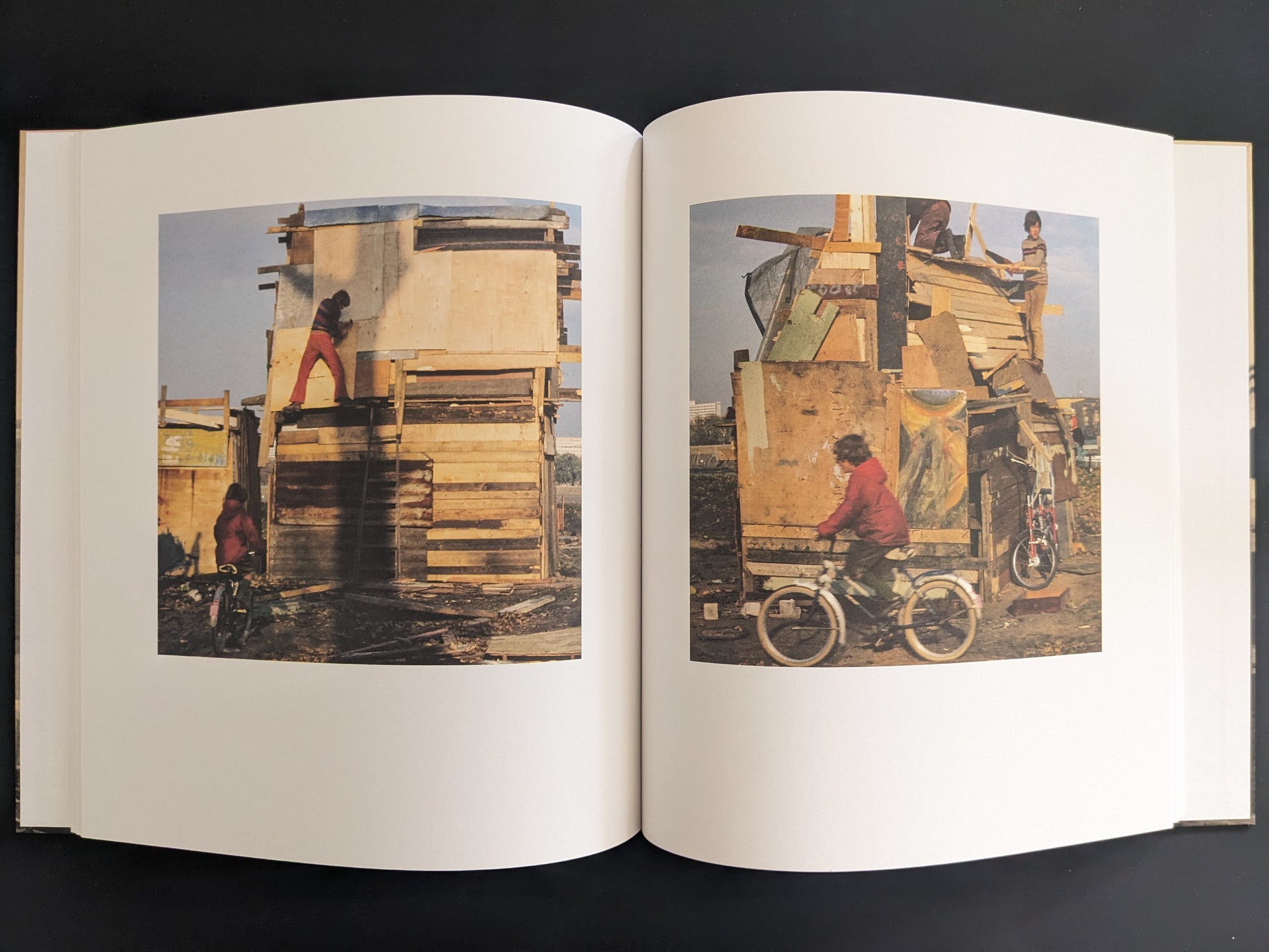 Open book spread with two colour photographs of children building tall wooden structures.
