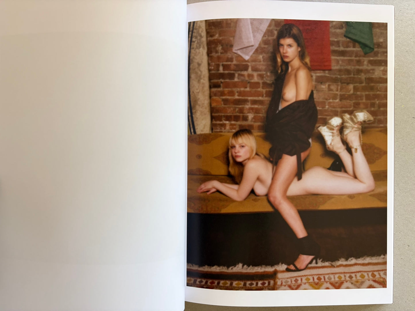 Open spread with two women posed on a sofa against a brick wall.