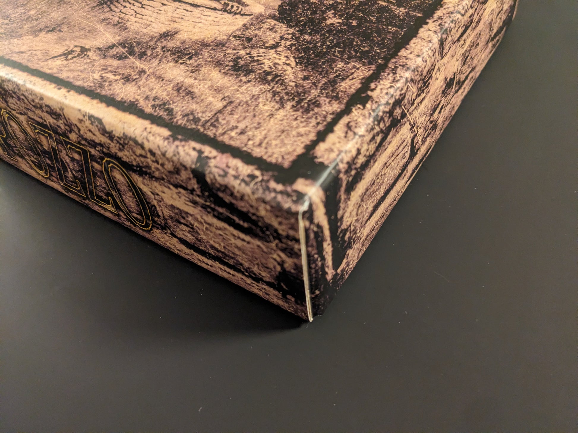 Close-up of the POZZO board game box corner showing minor wear and texture.