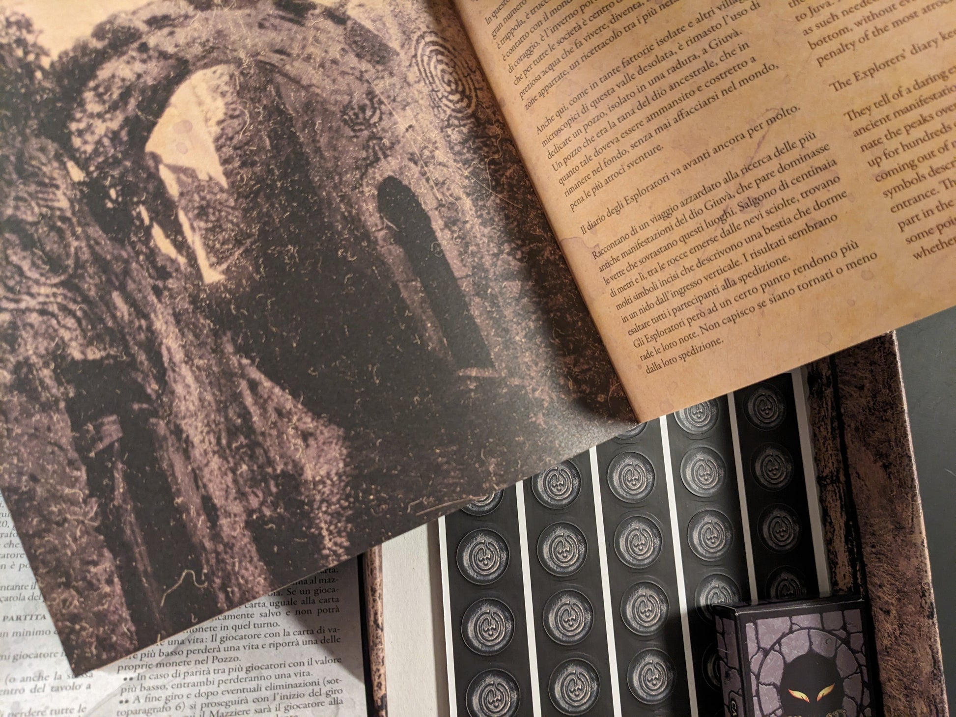 Open lore booklet from POZZO game showing dark horror illustrations and bilingual text.