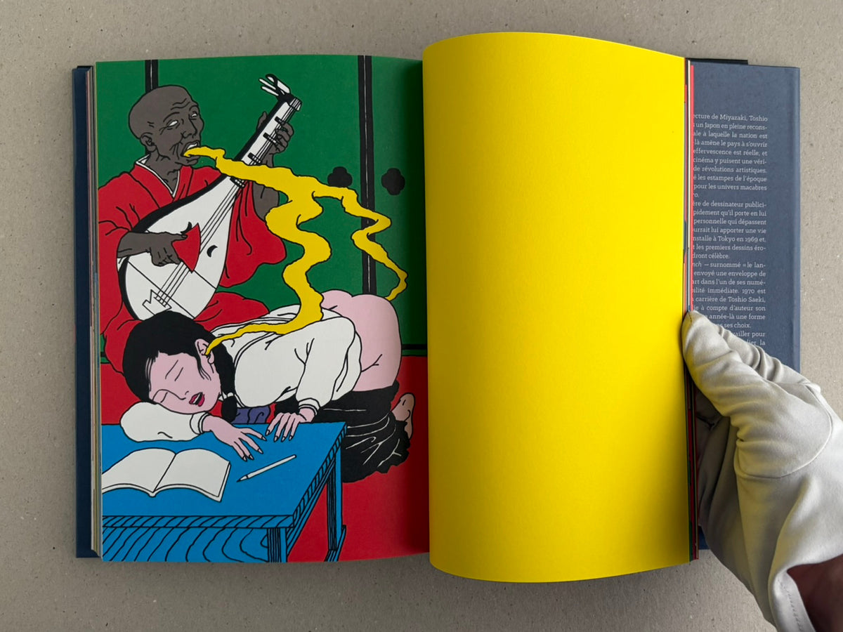 Rêve écarlate by Toshio Saeki open to a green-and-yellow spread with a seated figure and a blue figure beside a table.