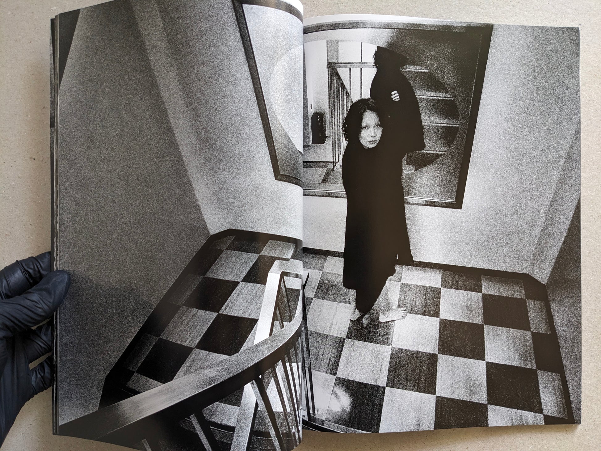 Woman in a dark coat standing in a stairwell with checkered floor, Record No. 50 by Daido Moriyama.