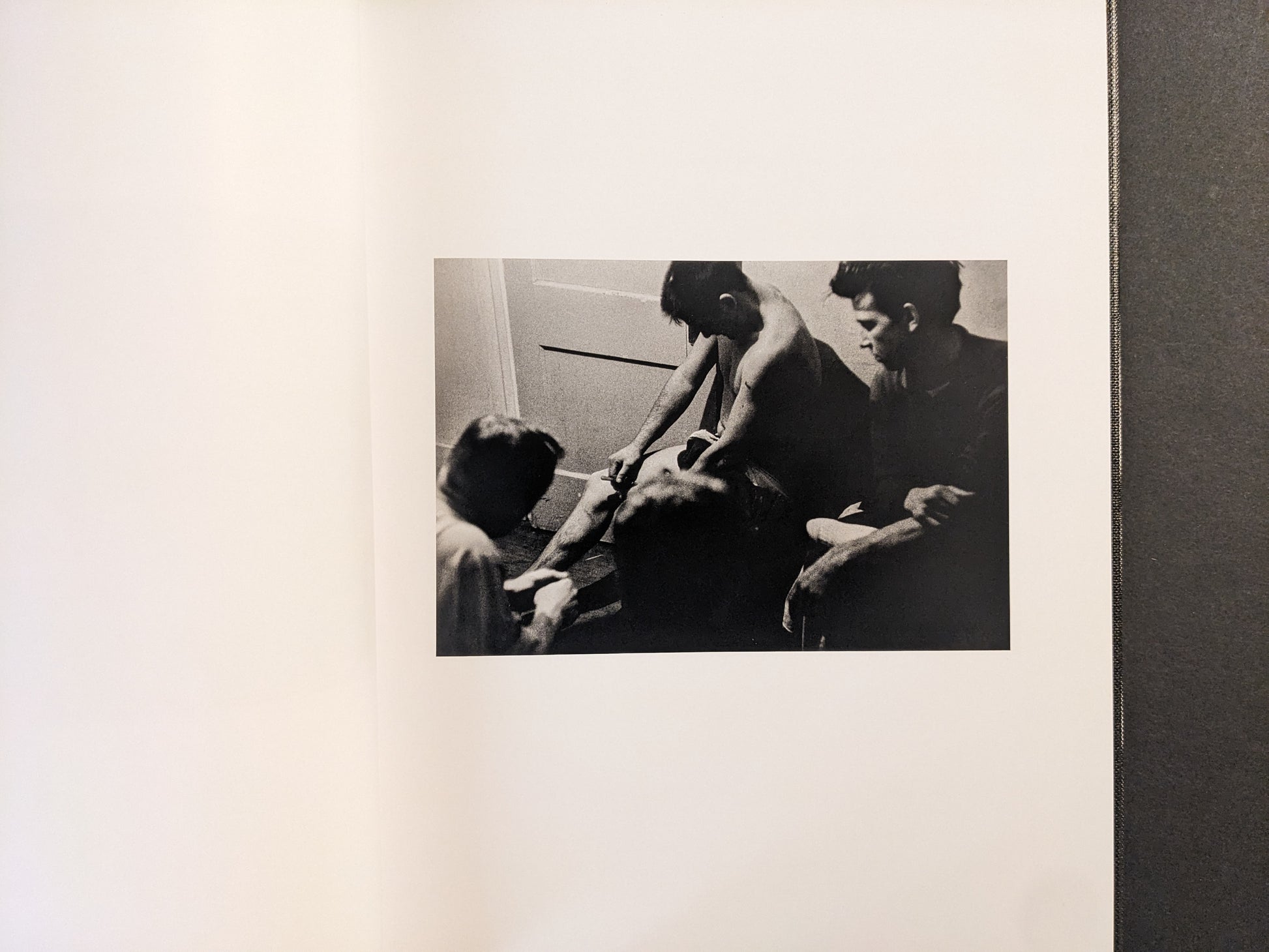Interior spread showing a group of people in a small room, black-and-white photograph.