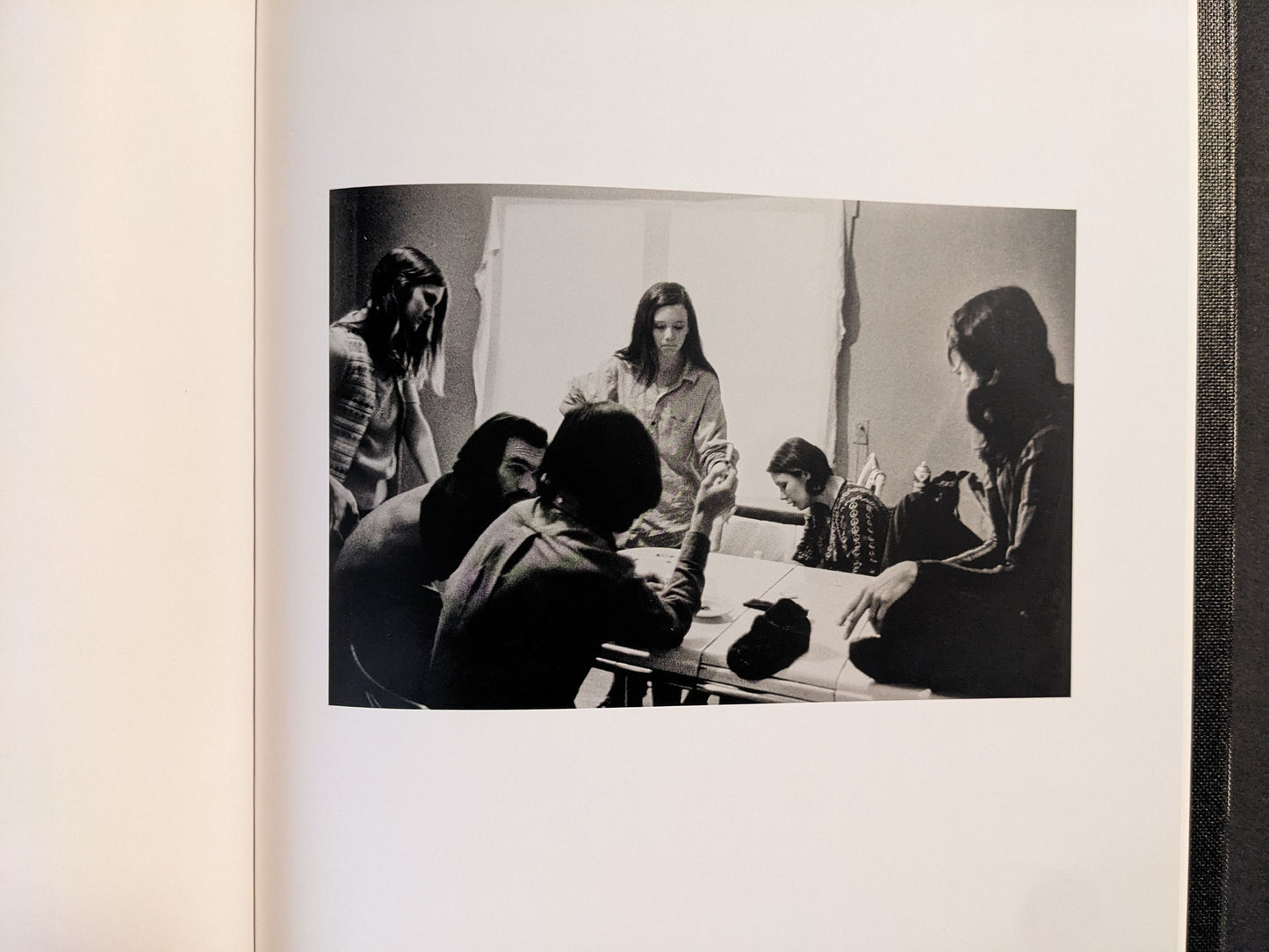 Interior spread showing a group gathered around a table, black-and-white photograph.