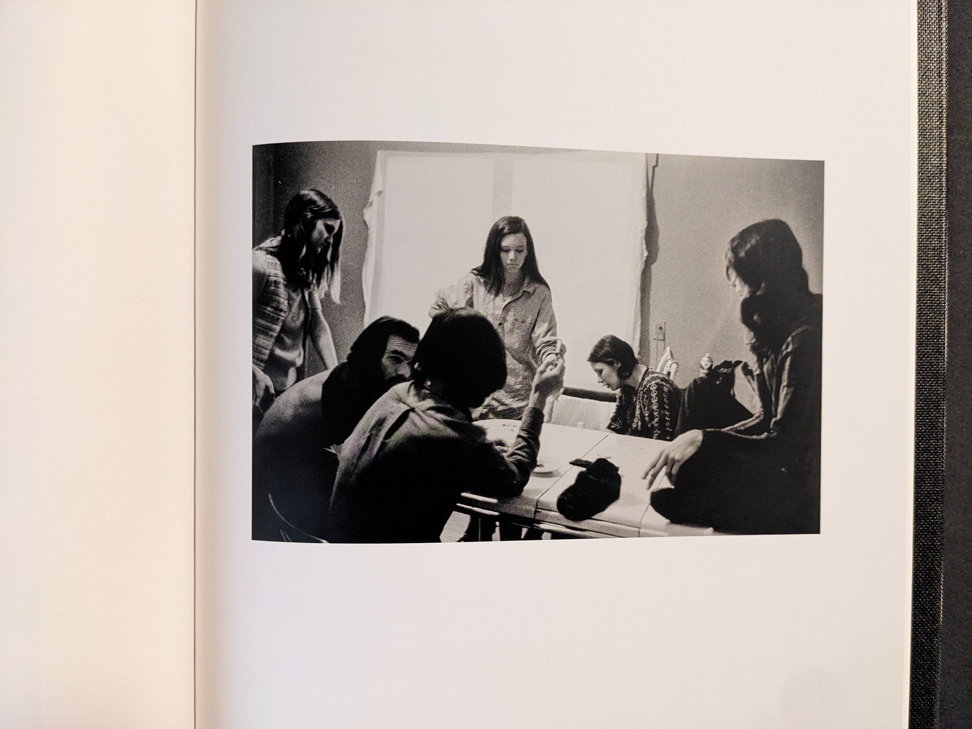 Interior spread showing a group gathered around a table, black-and-white photograph.