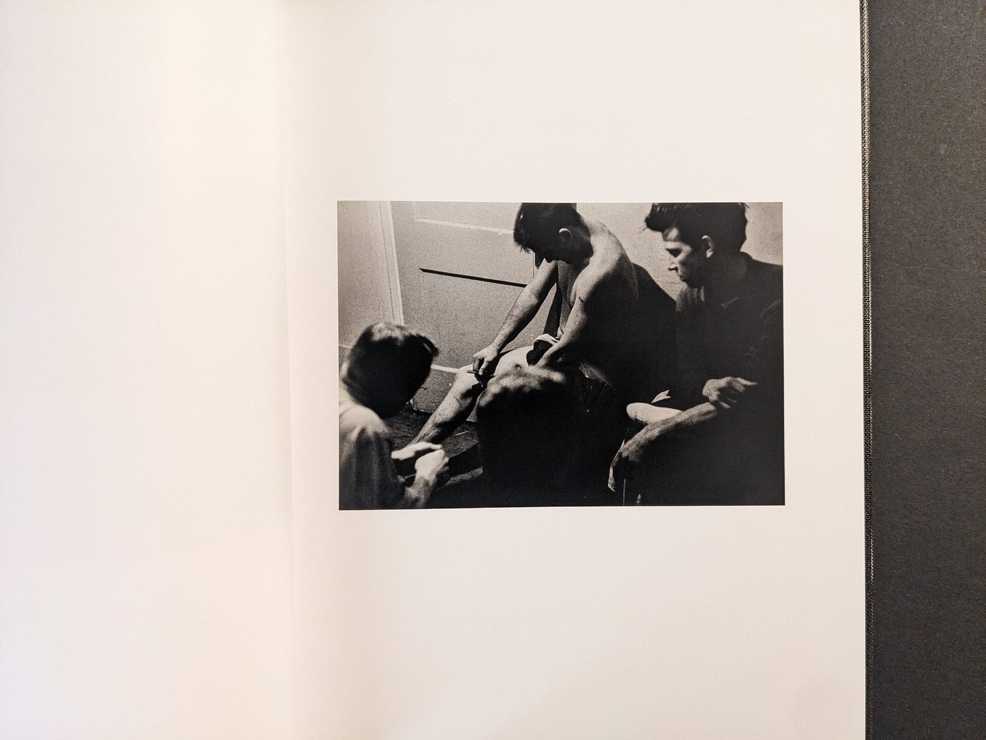 Interior spread showing a group of people in a small room, black-and-white photograph.