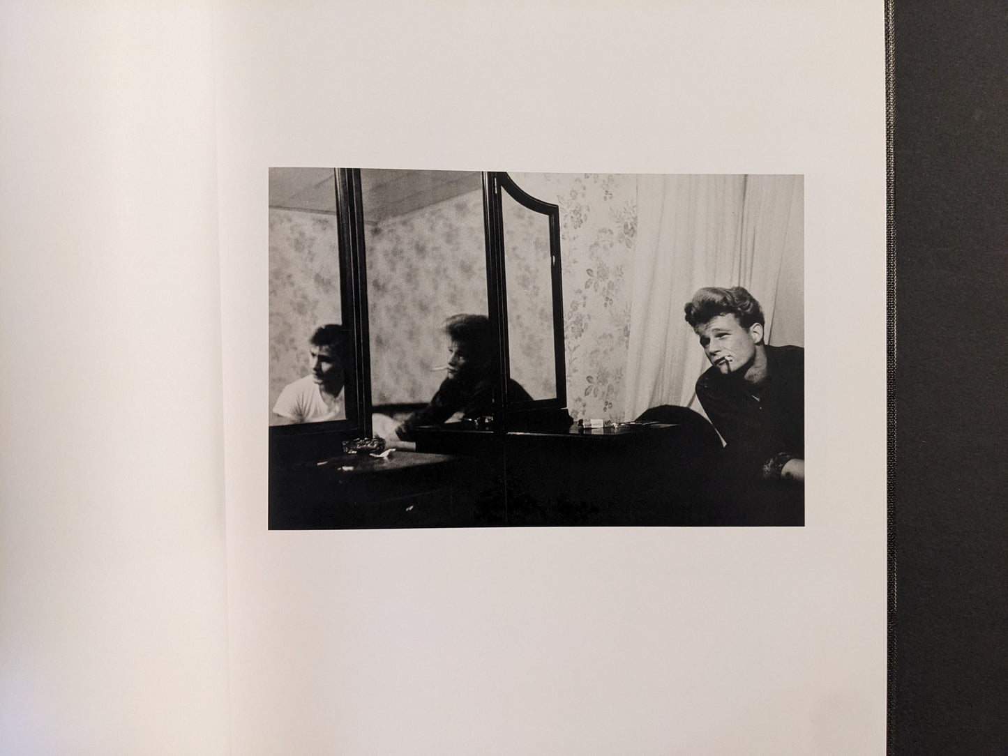 Interior spread showing a young man by a dresser mirror with a cigarette, black-and-white photograph.
