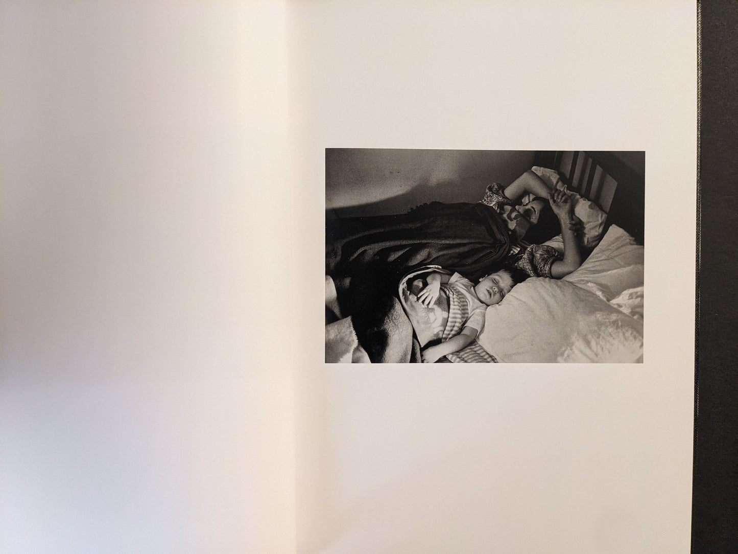 Interior spread showing an adult and a child asleep on a bed, black-and-white photograph.