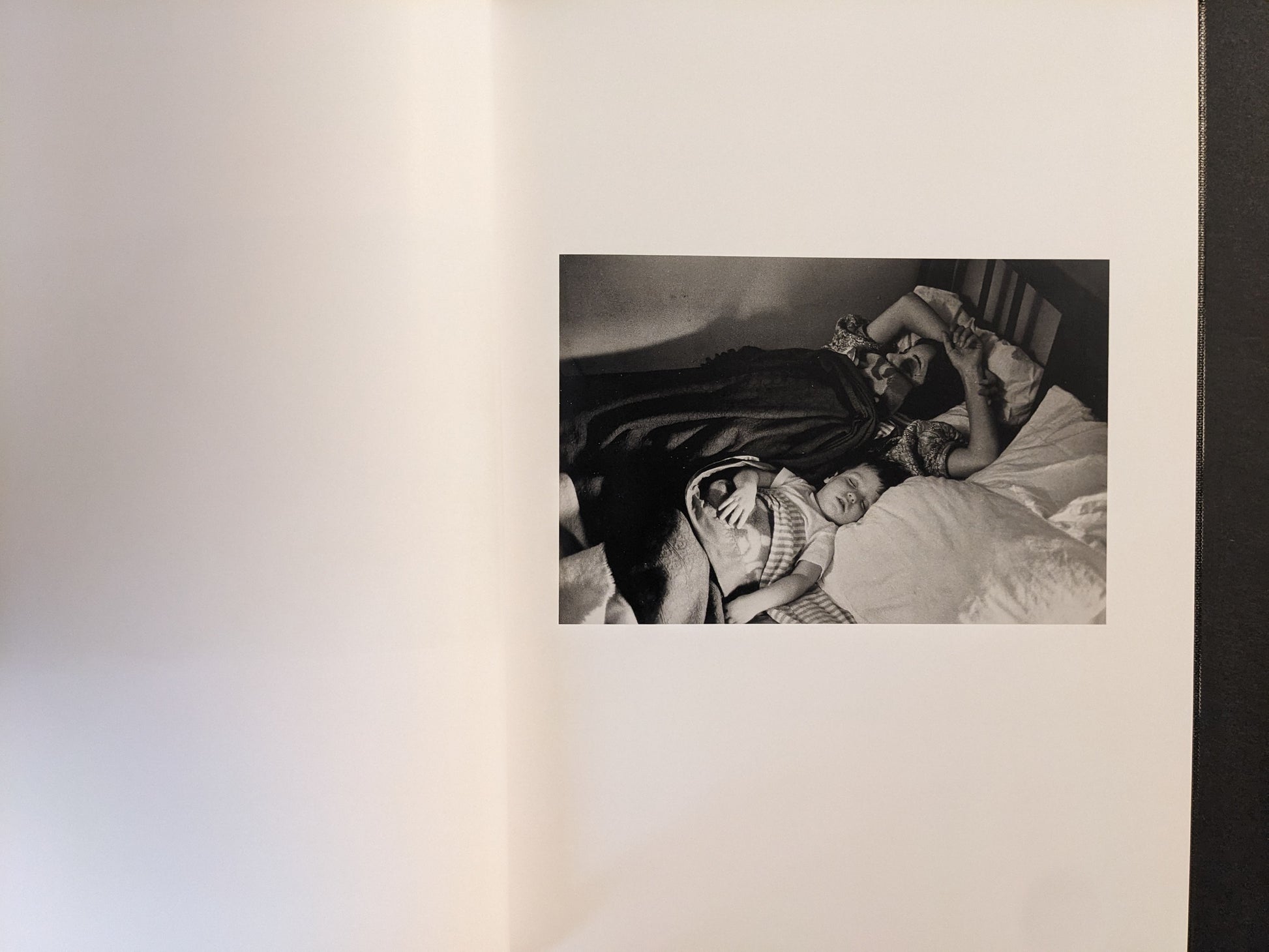 Interior spread showing an adult and a child asleep on a bed, black-and-white photograph.