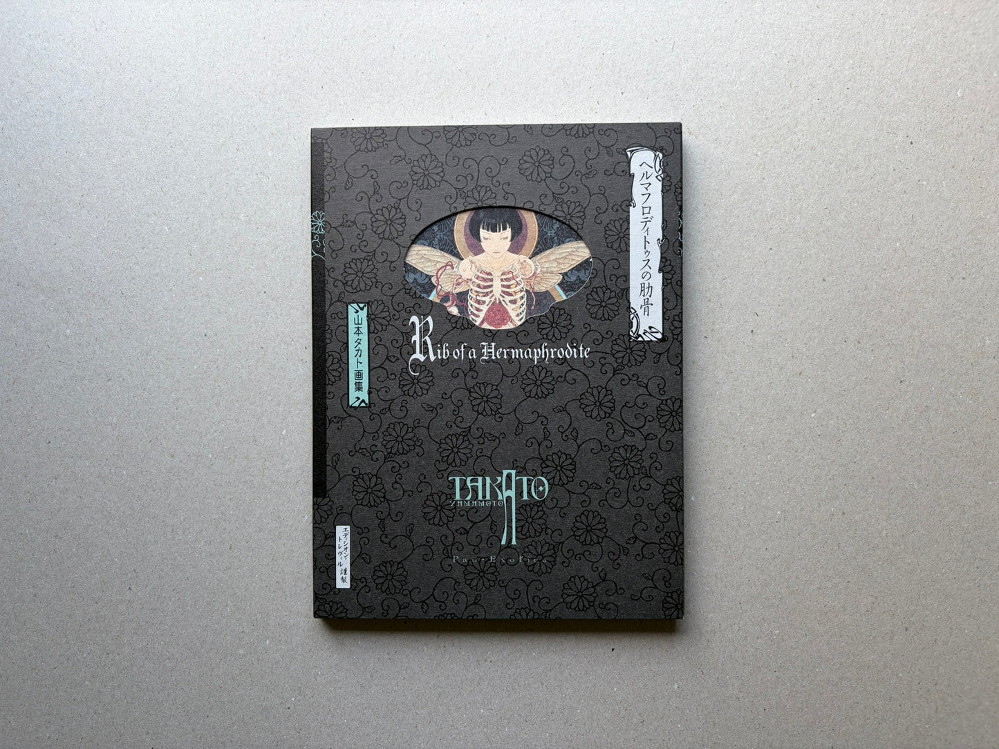 Rib of a Hermaphrodite by Takato Yamamoto, front cover of the New Black Edition with black patterned slipcase and oval cover illustration.
