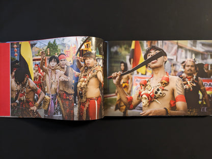 Ritual procession of Tatung participants in Borneo, wearing traditional attire and performing self-mortification with knives.