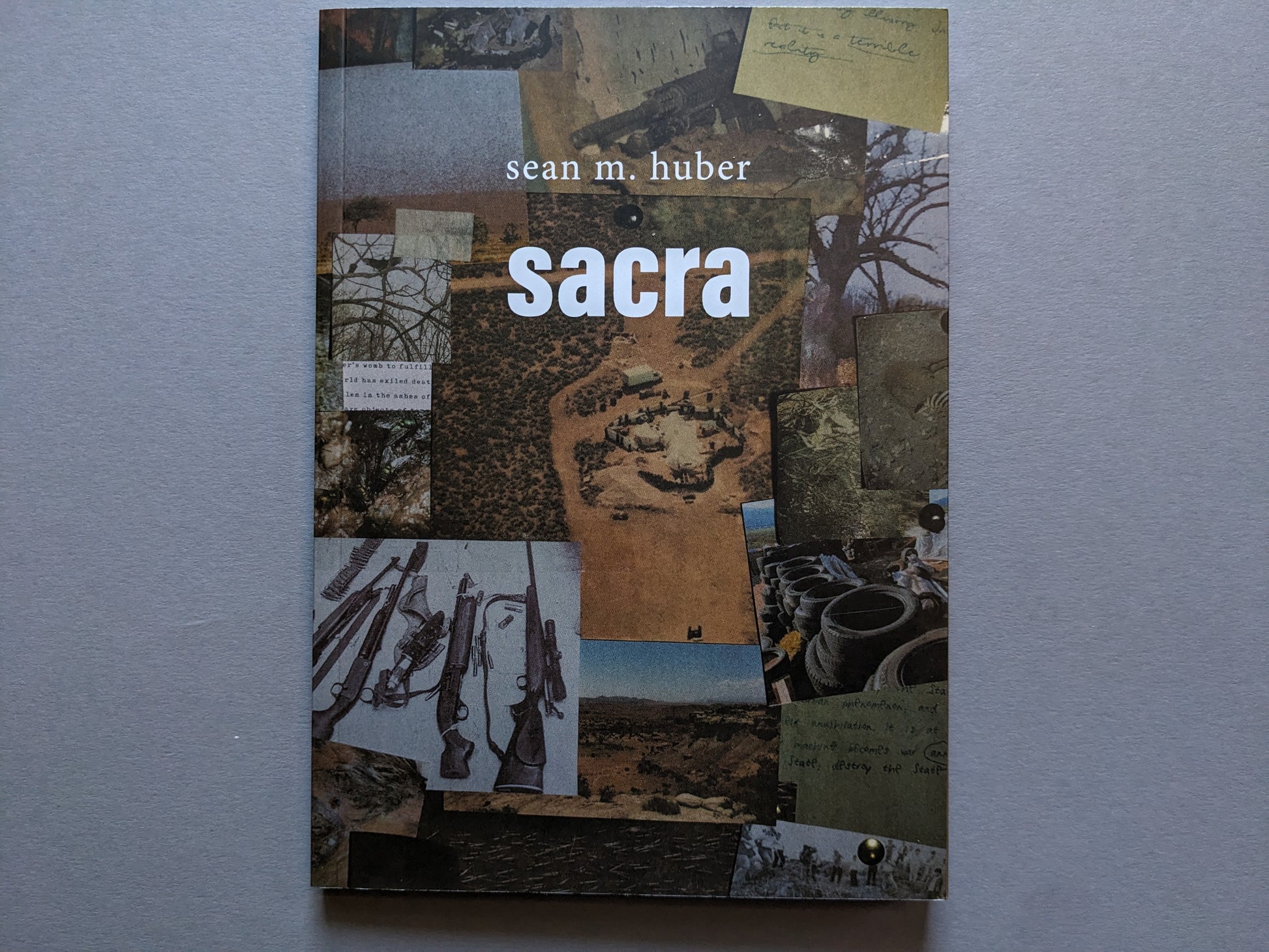 Front cover of "Sacra" by Sean M. Huber, collage of weapons, desert landscapes, and handwritten fragments