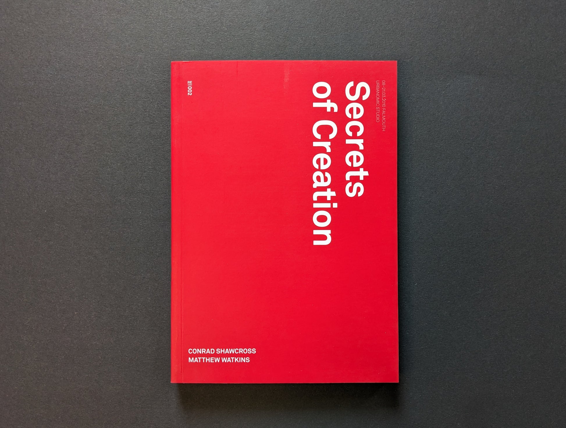 Front cover of Secrets of Creation with red minimalist layout and vertical title.