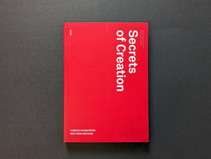 Front cover of Secrets of Creation with red minimalist layout and vertical title.