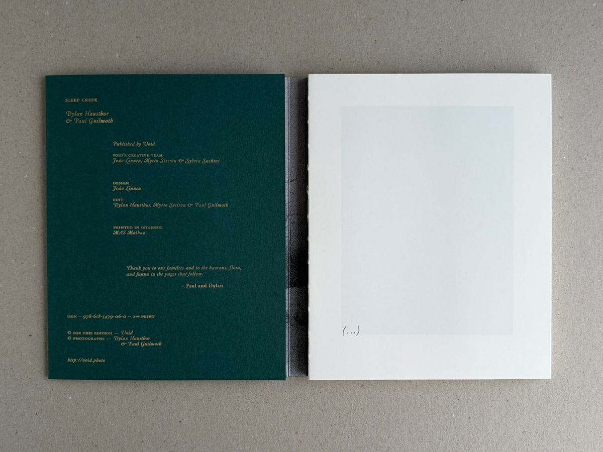 Open Sleep Creek photobook showing the green colophon page on the left and a pale blank page on the right.