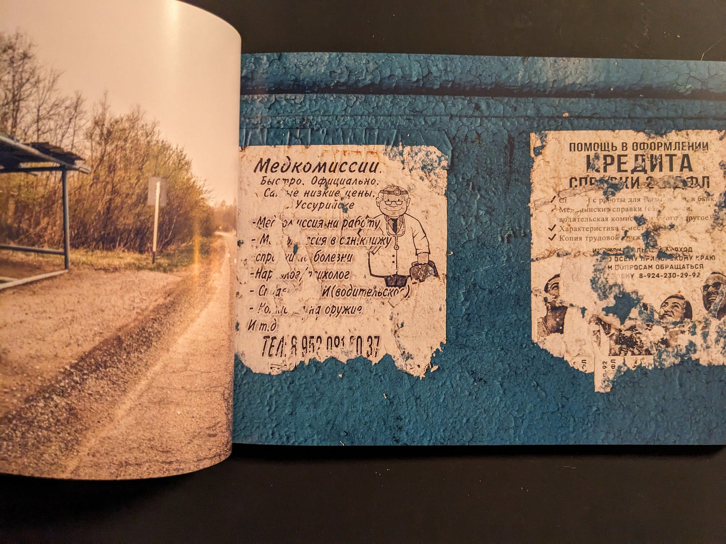 Interior spread with torn Russian posters on a blue wall beside the concrete underside of a Soviet-era bus shelter.