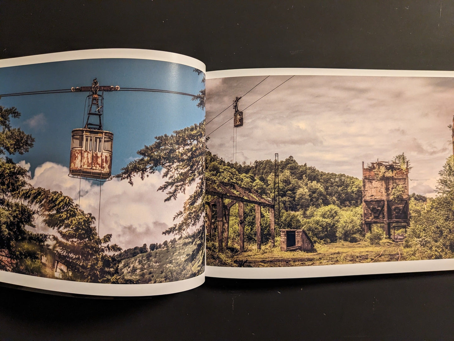 Interior spread: weathered cable-car tower with a rusted gondola suspended over trees.
