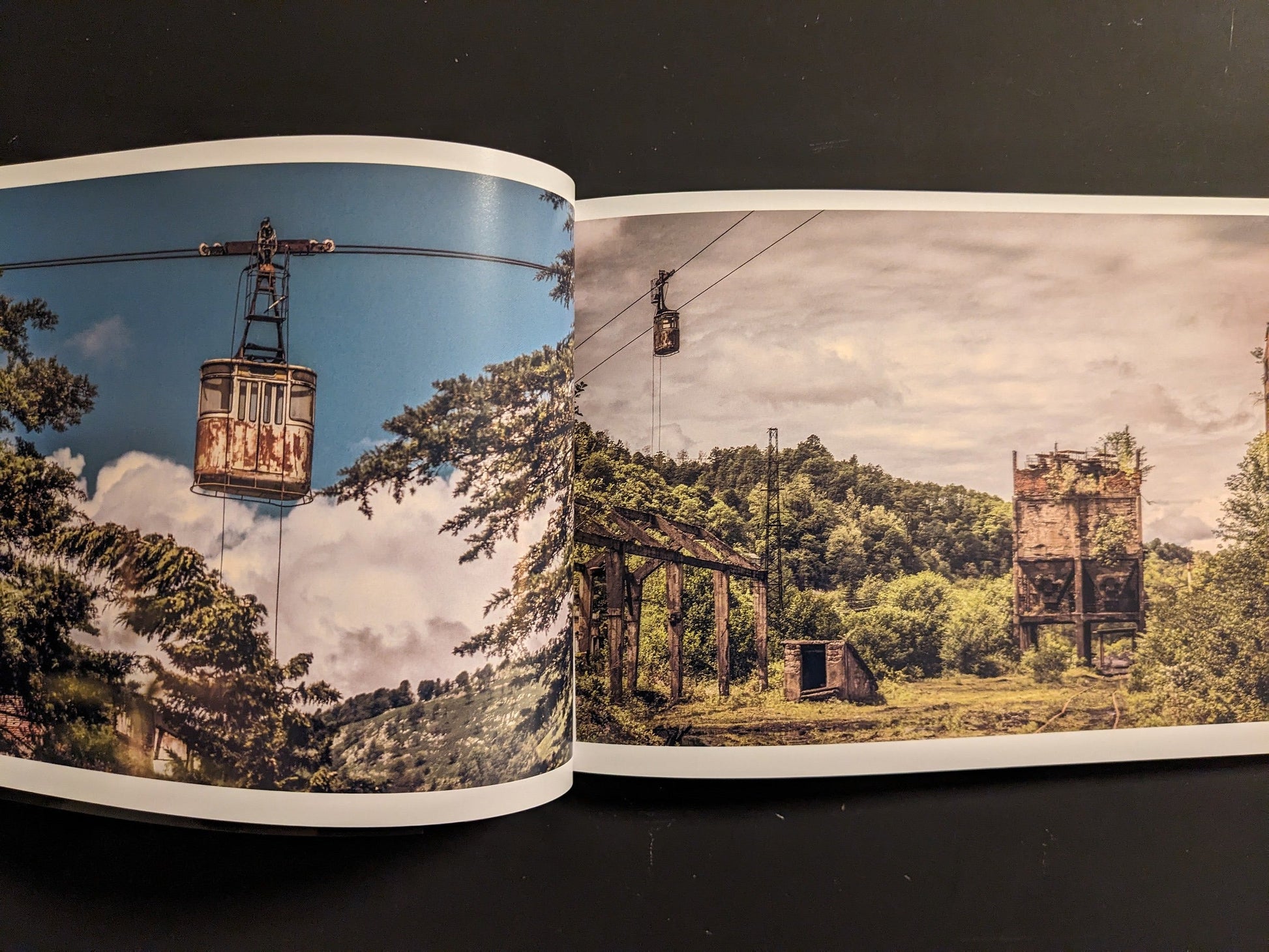 Interior spread: weathered cable-car tower with a rusted gondola suspended over trees.