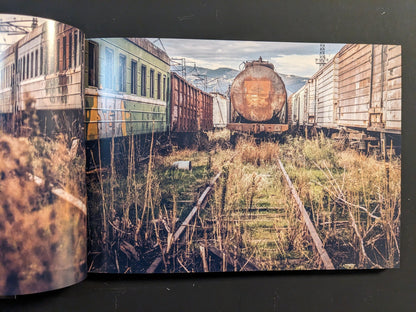 Interior spread: rusted freight cars and overgrown tracks in a derelict rail yard.