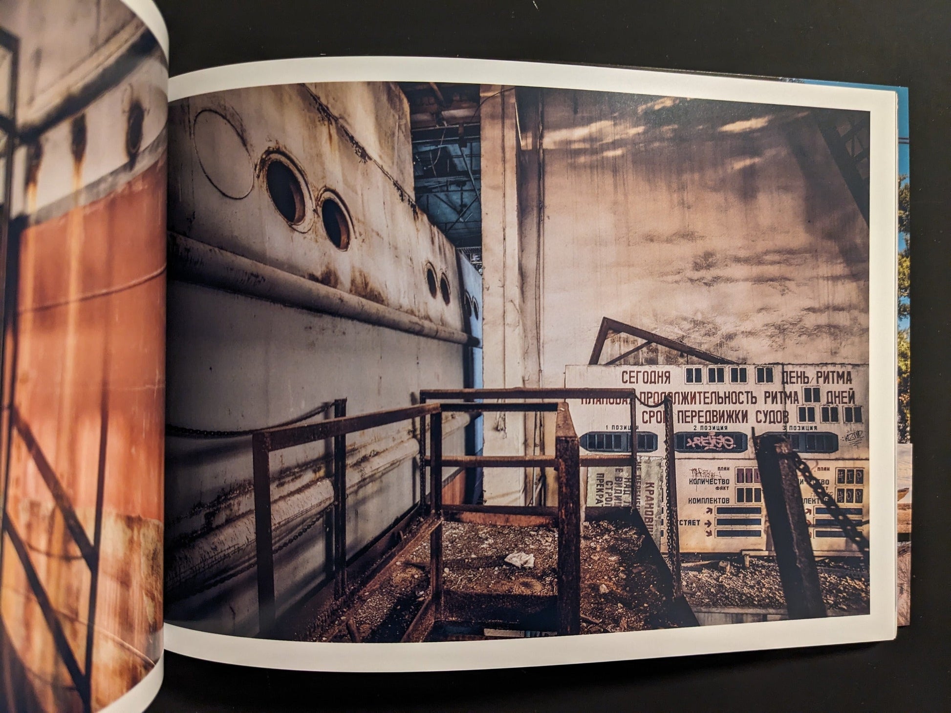Interior spread: industrial scene with Cyrillic warning signs beside a rusted ship hull and metal structure.