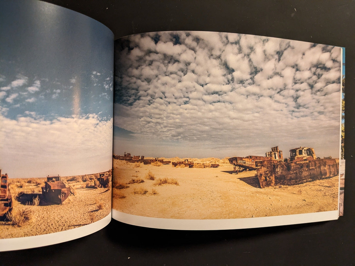 Interior spread: beached, rusting ships in a desert landscape; wide view of hulls on sand.