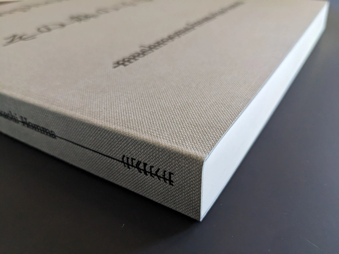 Spine view with grey textile cover and visible thread binding