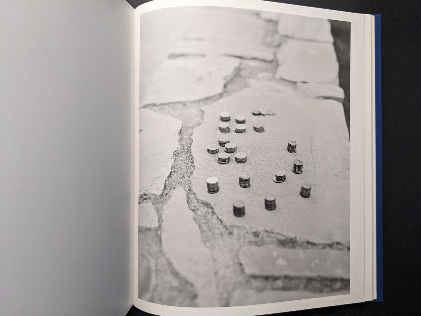 Black-and-white photo of small stacks of coins on stone pavement.