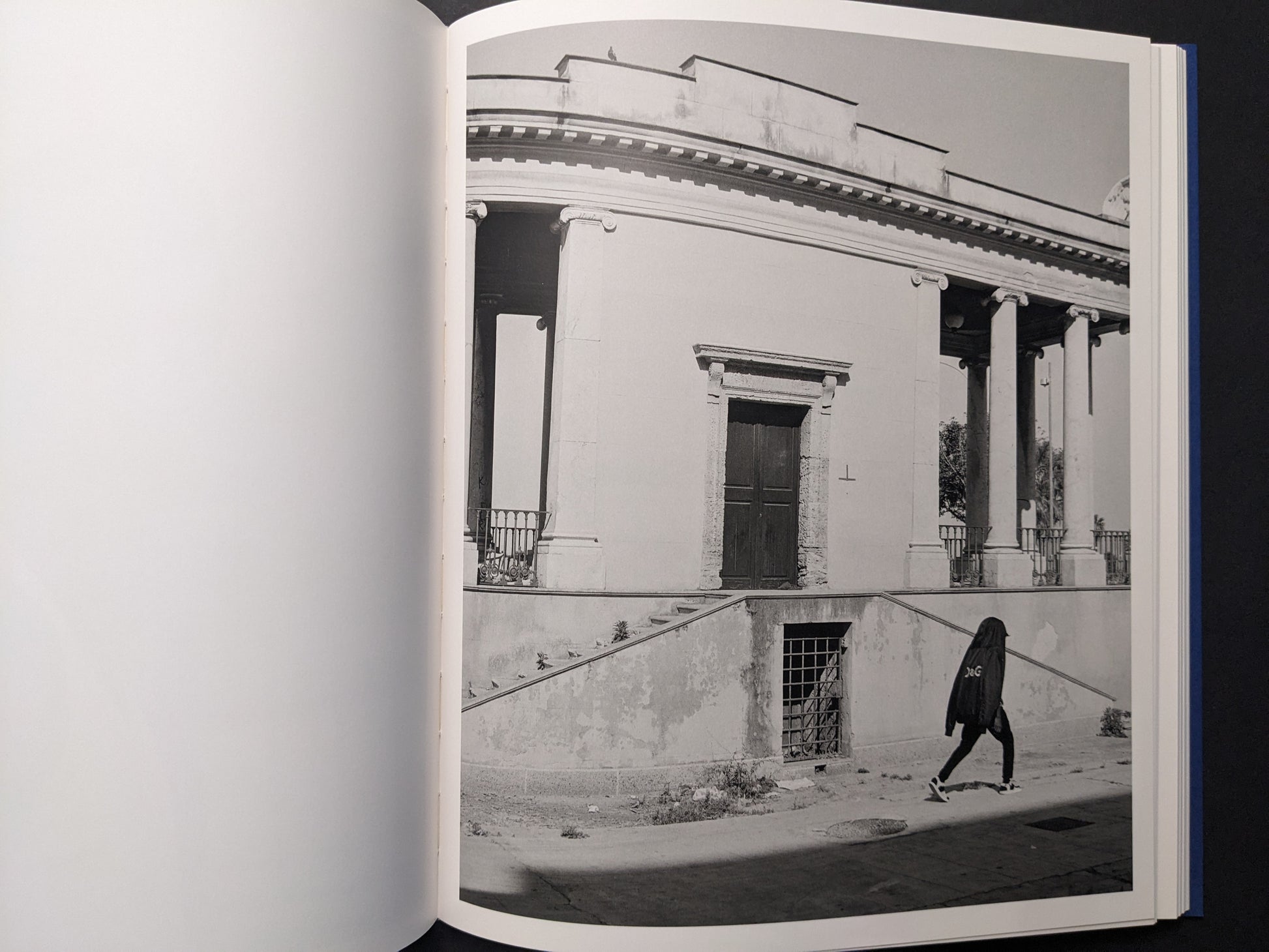 Black-and-white photo of a rotunda-like building with a lone passerby.