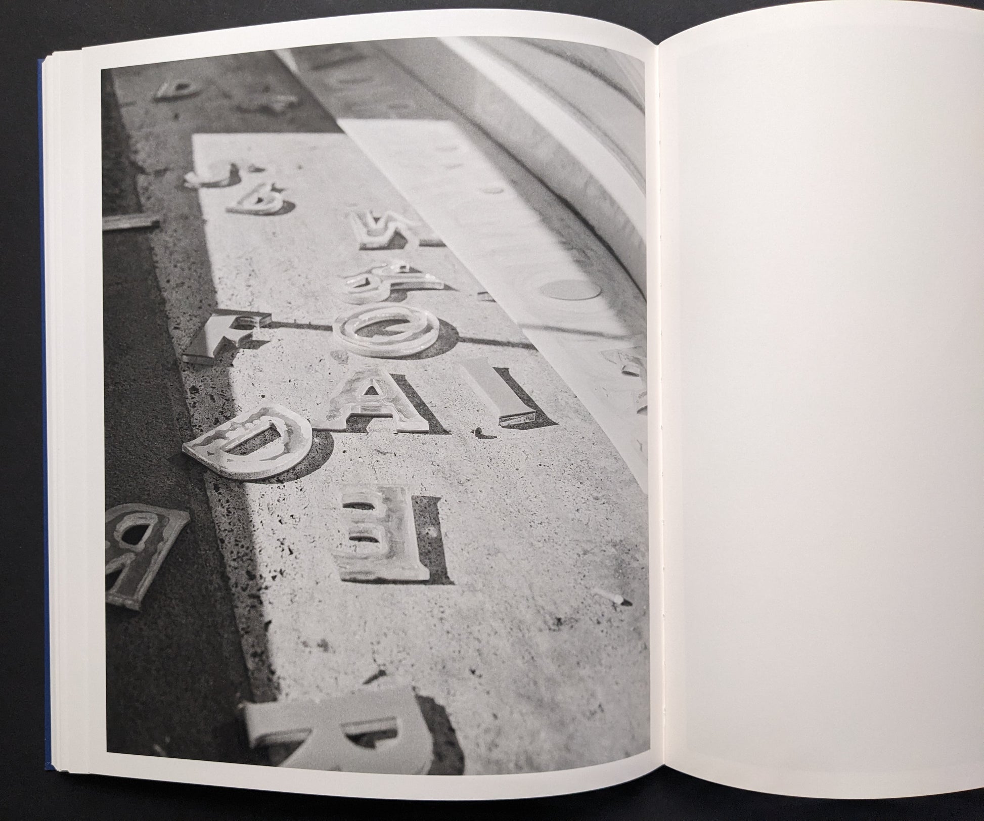 Black-and-white photo of scattered letterforms on dusty ground.