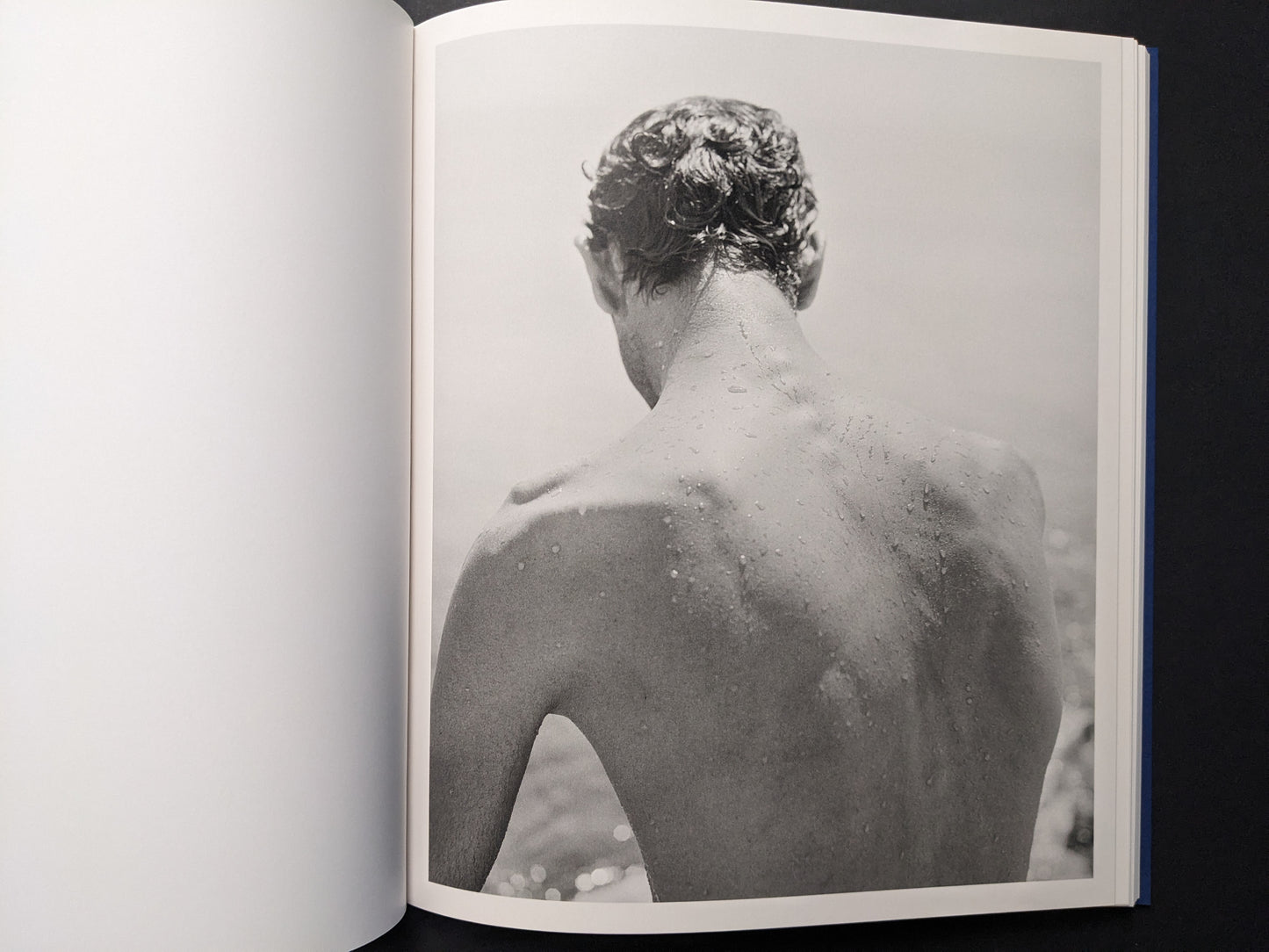 Black-and-white portrait of a man seen from behind, skin wet with droplets.